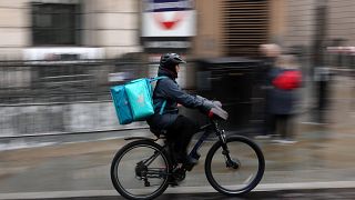  Колоездач на Deliveroo, каращ велосипед по пътя 