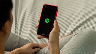 A man holding a phone with Spotify open