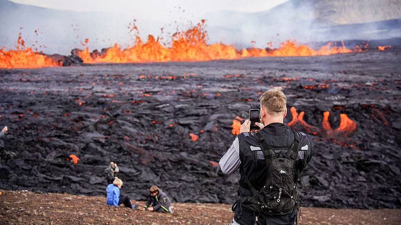 Menschen betrachten die Lava, die am 3. August 2022 aus dem Vulkan Fagradalsfjall in Island fließt.