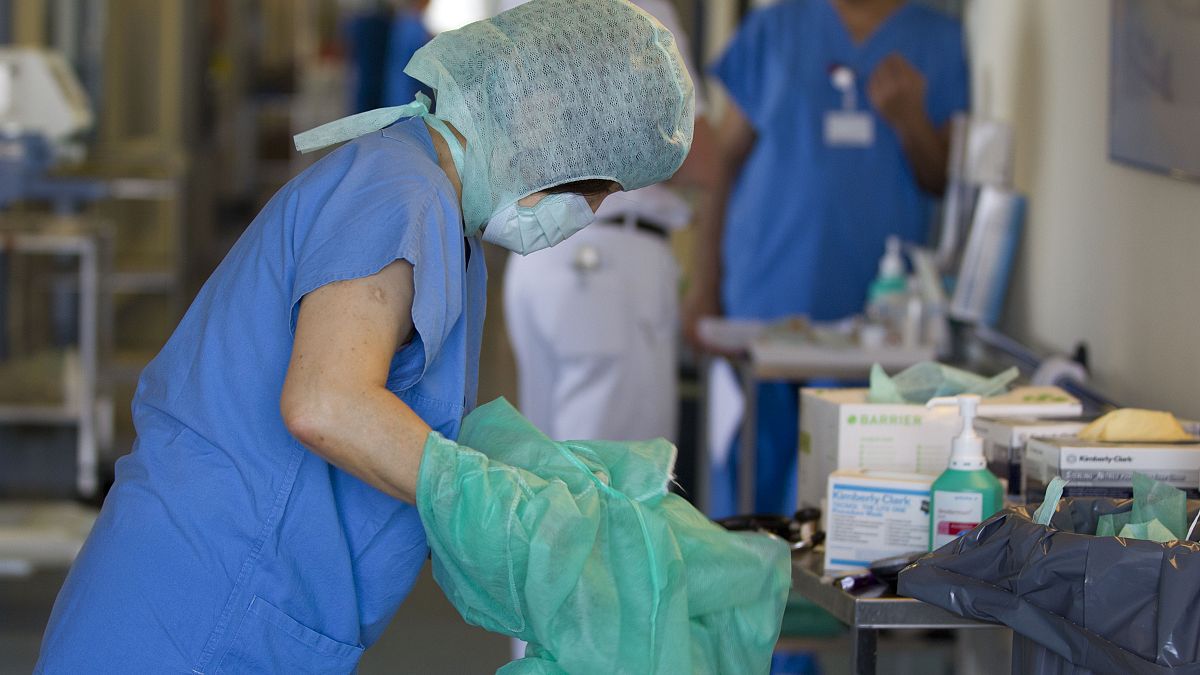 A nurse changes her protective clothing after treating an E. coli patient in Germany.