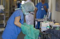 A nurse changes her protective clothing after treating an E. coli patient in Germany.