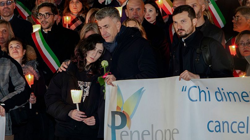 Gino Cecchettin, hugging his daughter Elena, attends a torchlit procession in Vigonovo, near Venice, northern Italy, Sunday, Nov. 19, 2023.