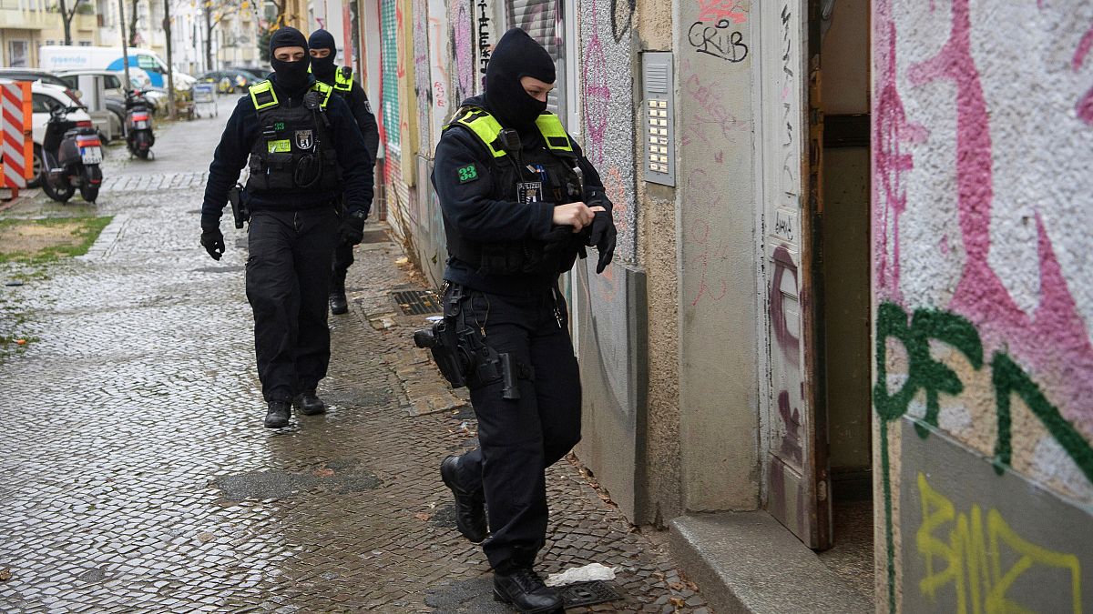 Agentes da polícia dirigem-se para a entrada de um edifício durante uma rusga em Berlim, Alemanha.