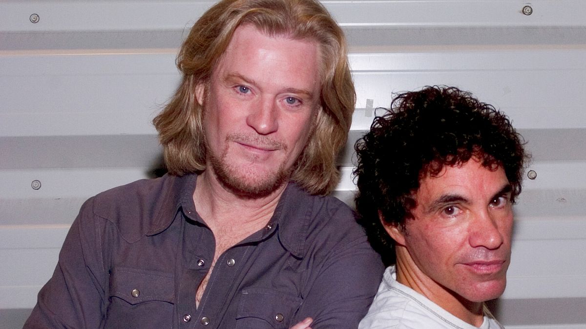 Vocalists and guitarists Daryl Hall and John Oates take a moment before their performance at the FleetBoston Pavilion in Boston, Saturday, July 17, 2004.