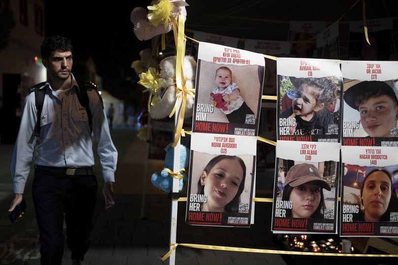 A member of Israeli security forces looks at posters of children held hostage by Hamas in the Gaza Strip, displayed ahead of an anticipated hostage release, in Israel.