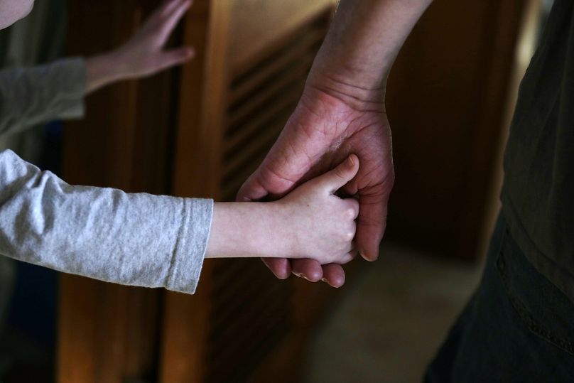 An autistic boy holds the hand of his adoptive father.