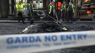 A car burns as Irish policemen stand at the scene of an attack in Dublin city centre, Thursday Nov. 23, 2023