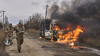 Soldados ucranianos pasan junto a un autobús ardiendo tras ser atacado por un dron ruso cerca de Bakhmut, en la región ucraniana de Donetsk, el jueves 23 de noviembre