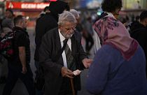 A man purchases food from a street vendor at Kadikoy ferry terminal in Istanbul, Thursday, Nov. 16, 2023. 