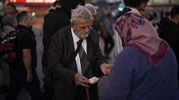 A man purchases food from a street vendor at Kadikoy ferry terminal in Istanbul, Thursday, Nov. 16, 2023. 