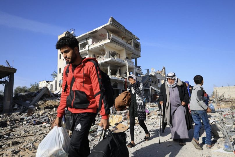 I palestinesi camminano tra le macerie al loro ritorno a Khan Yunis per ispezionare le loro case dopo settimane di bombardamenti israeliani