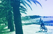 A man rides a bicycle by the beach in Oeiras, just outside Lisbon, July 2023