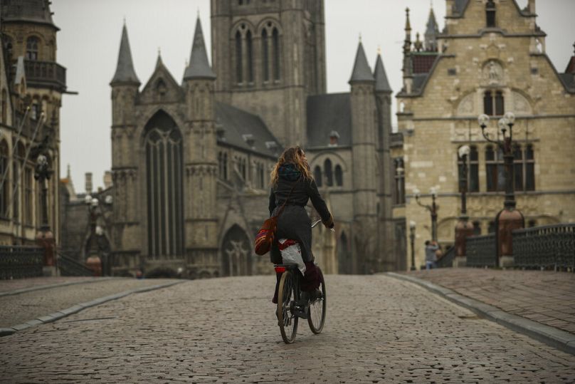 A woman rides a bicycle in downtown Ghent, March 2020
