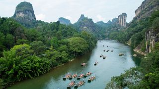 Tourists on bamboo rafts tour the Jiuqu river at a Wuyi mountain scenic area in southeast China's Fujian Province on 3 October 2023.