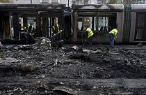 Destroços de um tram e um autocarro queimados são retirados da rua esta sexta-feira, no rescaldo da violência em Dublin na noite de quinta-feira.