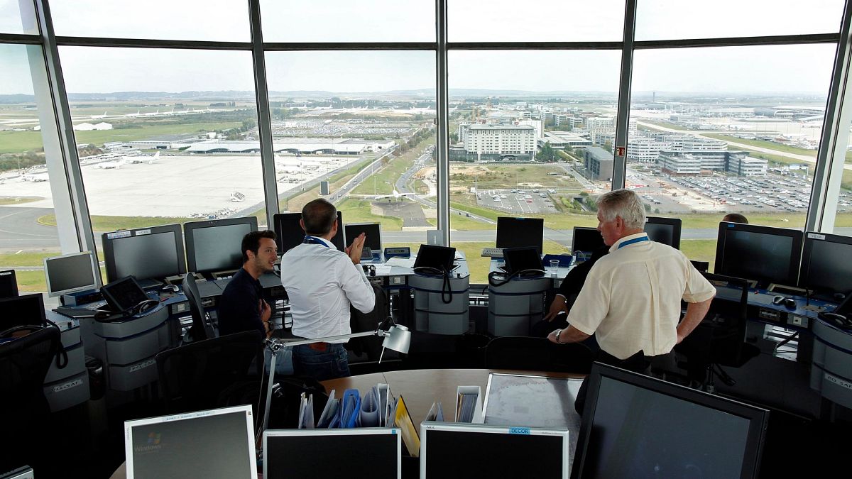 An air-traffic controller (right) speaks with visitors in the main control tower at the Charles de Gaulle International Airport in Roissy, near Paris, September 2014. 