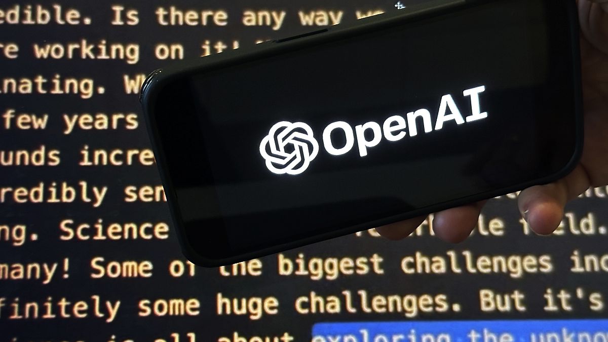 The OpenAI logo appears on a mobile phone in front of a screen showing a portion of the company website in this photo taken on Tuesday, Nov. 21, 2023 in New York. 