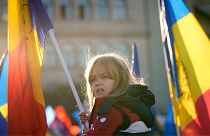 Une petite fille agite un drapeau lors d'une manifestation contre le gouvernement et les restrictions organisée par l'Alliance pour l'unité des Roumains (AUR), un parti d'extrême droite, à Bucarest.