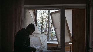 Un hombre cubre las ventanas de su casa tras el ataque a Kiev.