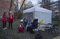 امدادگران در کنار ساکنان آپارتمانی آسیب دیده در پی حمله پهپادی روسیه به کی‌یف 