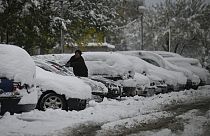 Anwohner in einem Vorort von Sofia kratzt Schnee von seinem Auto