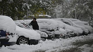 Anwohner in einem Vorort von Sofia kratzt Schnee von seinem Auto