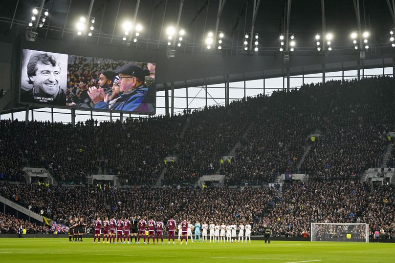 Players and fans applaud during a tribute to former England player and coach Terry Venables, shown on the video screen, before a Tottenham-vs-Aston Villa match on Sunday