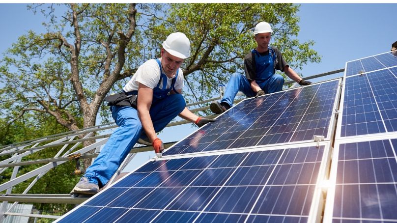Workers install solar panelling
