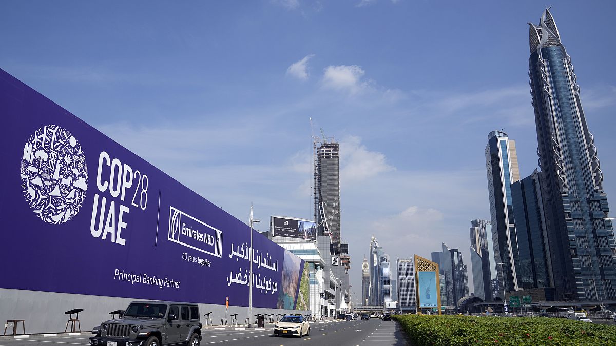 Carros passam por um cartaz publicitário da COP28 na autoestrada Sheikh Zayed no Dubai, Emirados Árabes Unidos, segunda-feira, 27 de novembro de 2023.