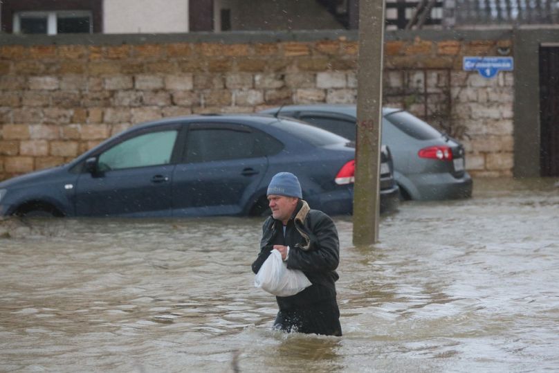 A man walks in a flooded street during an evacuation of residents of the village of Pribrezhnoe in Crimea on November 27, 2023, following a storm.