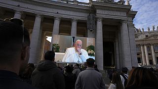 A giant screen broadcasts Pope Francis coughing during the Angelus noon prayer, from the chapel of the hotel at the Vatican grounds where he lives, Sunday, Nov. 26, 2023. 