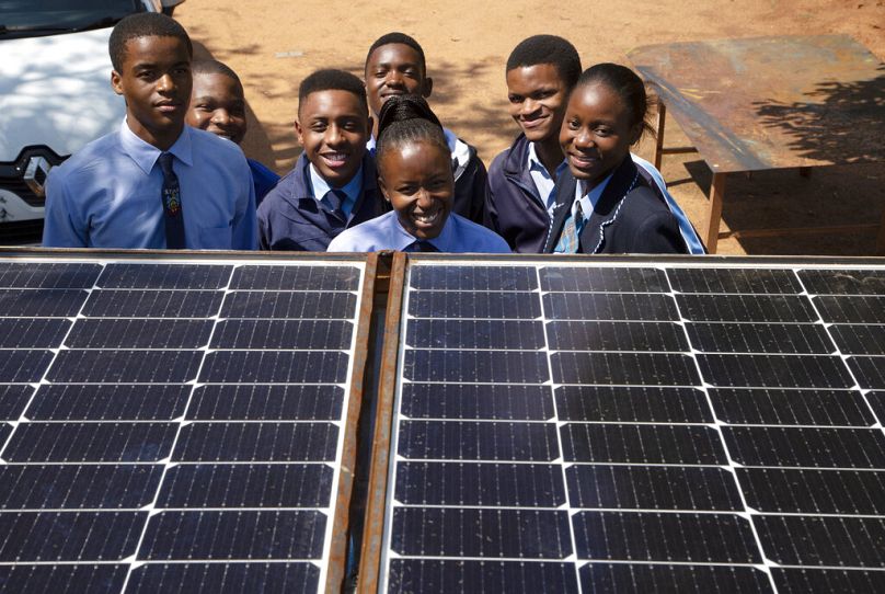 Students from the Soshanguve Automotive School of Specialization pose for a photograph behind solar panels on a train roof, north of Pretoria, November 2022