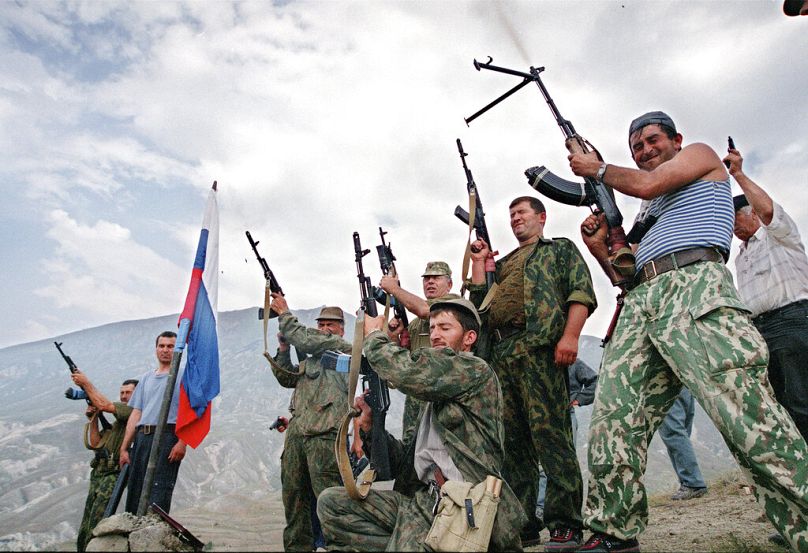 Des troupes du ministère russe de l'Intérieur et des volontaires daghestanais tirent des coups de feu en signe de célébration dans le village de Tando, en août 1999