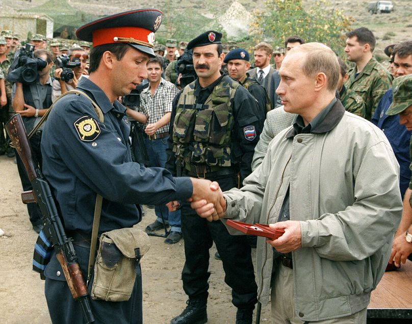 Russian Prime Minister Vladimir Putin, right, presents an award to a local police officer at a Russian military base in the mountains of the Botlikh region, August 1999
