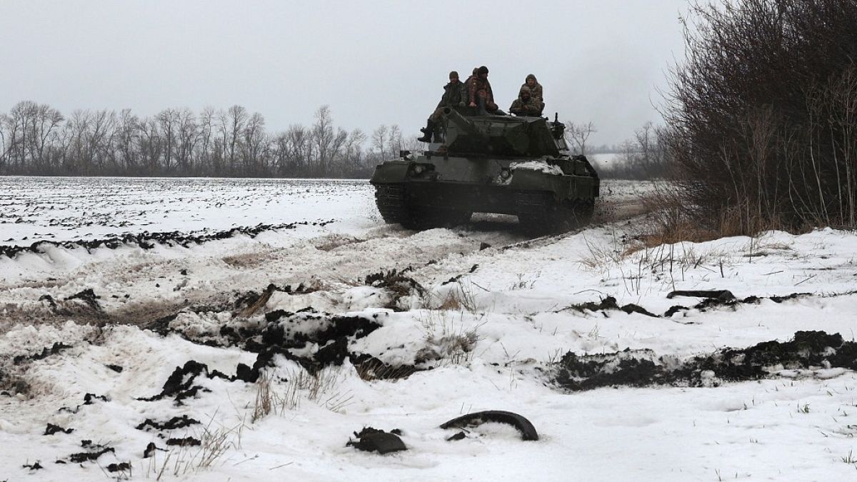 Ukrainian tankists ride on a tank Leopard 1A5 on a snow-covered ground not far from the front line in Kharkiv region on November 24, 2023.