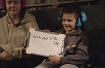 Otages israéliens libérés Tal Goldstein Almog, 9 ans, à droite, tenant un panneau qui dit en hébreu "Flying abroad" assis à côté de sa sœur Agam Goldstein-Almog, 17 ans,