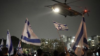 Menschen schwenken israelische Flaggen, als ein Hubschrauber mit von der Hamas freigelassenen Geiseln in Israel landet. 
