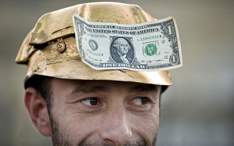 A man wears a dollar bill on a miner's helmet painted in the colour of gold during a protest in Bucharest, September 2021