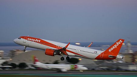 An easyJet Airbus A321 takes off from Lisbon airport, while a TAP Air Portugal airplane taxis in the background, Wednesday, Jan. 25, 2023.