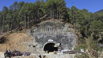 Menschen beobachten Rettungs- und Hilfsmaßnahmen an der Stelle eines im Bau befindlichen Straßentunnels, der im indischen Bundesstaat Uttarakhand eingestürzt ist, 
