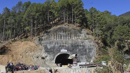 Menschen beobachten Rettungs- und Hilfsmaßnahmen an der Stelle eines im Bau befindlichen Straßentunnels, der im indischen Bundesstaat Uttarakhand eingestürzt ist, 