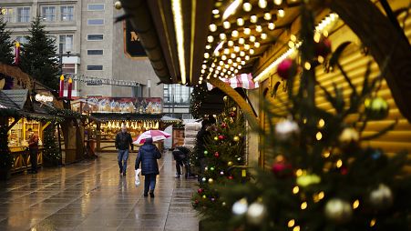 People walk across a Christmas Market on a rainy morning in central Berlin, Germany