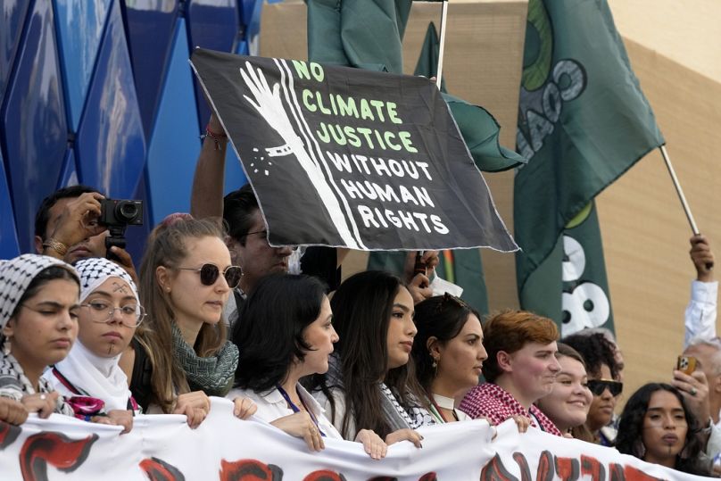 Pro-Palestinian demonstrators participating in a protest against the Israel-Hamas war hold a sign at the COP28 Climate Summit in Dubai, United Arab Emirates.