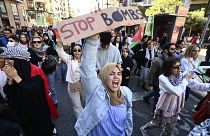Um manifestante grita palavras de ordem enquanto segura um cartaz com os dizeres "Parem as bombas" durante uma manifestação de apoio ao povo palestiniano em Valência, no dia 19.11.