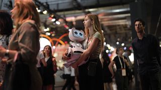 A woman carries a robot during the Vivatech show in Paris, France, Wednesday, June 14, 2023.