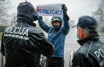 Ein Demonstrant in Ljubljana mit einem Plakat mit der Aufschrift "Heuchler" stellt sich während der Gedenkfeier für die Opfer von COVID-19 den Polizisten entgegen.