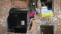 Des habitants ukrainiens escaladent leur maison détruite par des bombardements russes en mai 2022.