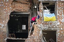 2022. május 21-én, szombaton az ukrajnai Kijevhez közeli Irpinben a lakosok felmásznak az orosz lövöldözés miatt tönkretett házukba, hogy kivigyék holmijukat.