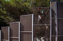 یک مهاجر غیرقانونی از حصار عبور می‌کند تا از مرکز عملیاتی «نقطه کانونی در جزیره لامپدوسای ایتالیا» خارج شود.