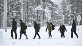 Guardie di frontiera finlandesi scortano i migranti in arrivo al posto di frontiera internazionale Raja-Jooseppi tra Russia e Finlandia, a Inari, Finlandia settentrionale, 25/11/23.